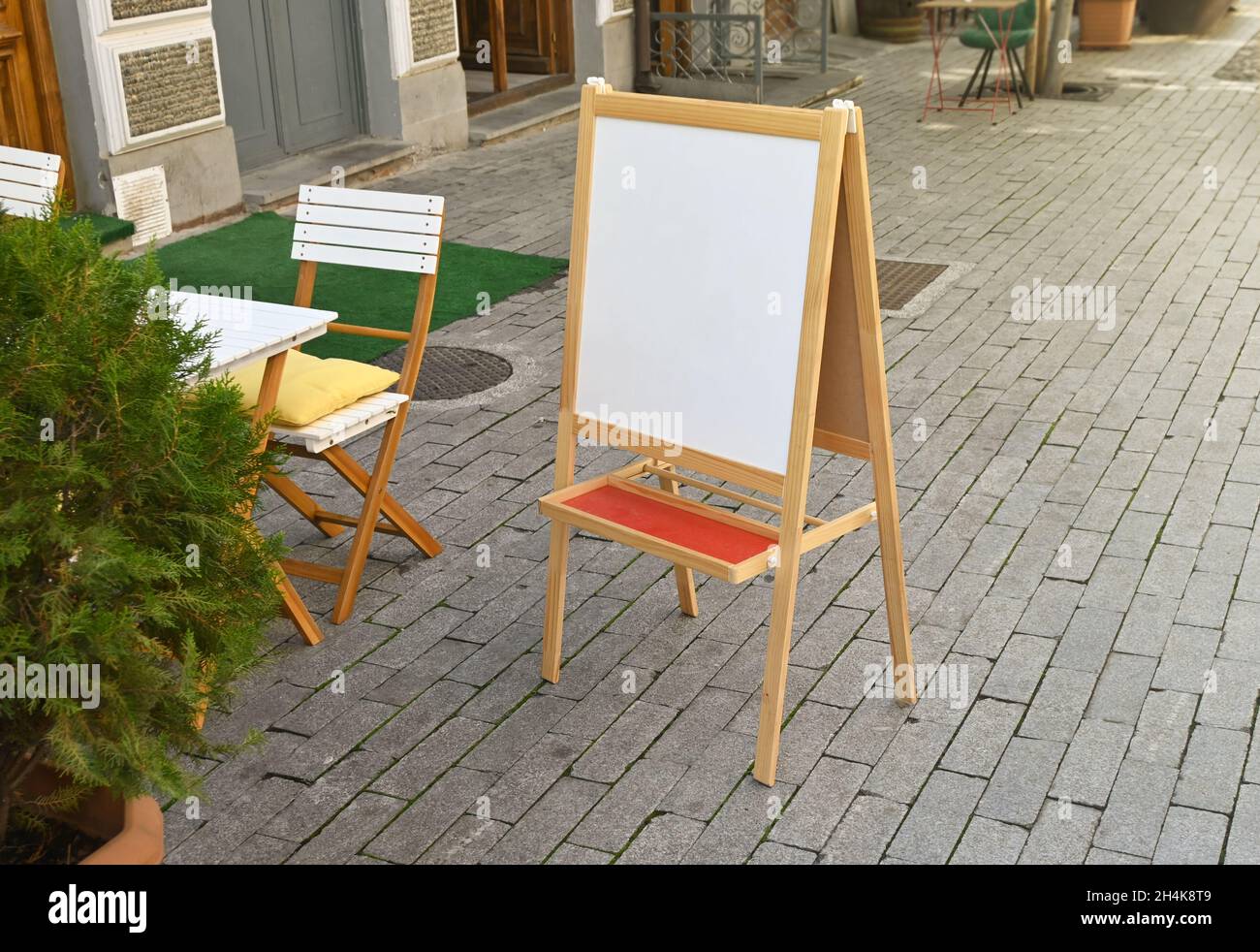Im Sommer steht ein weißer, unbeschriftete Schild für das Straßencafé Stockfoto