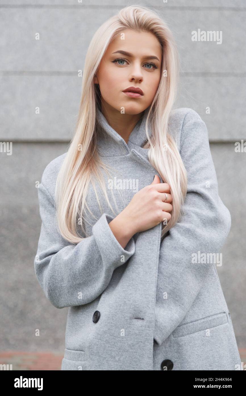 Porträt einer schönen jungen blonden Frau in grauem Mantel. Street-Fashion-Look. Stockfoto