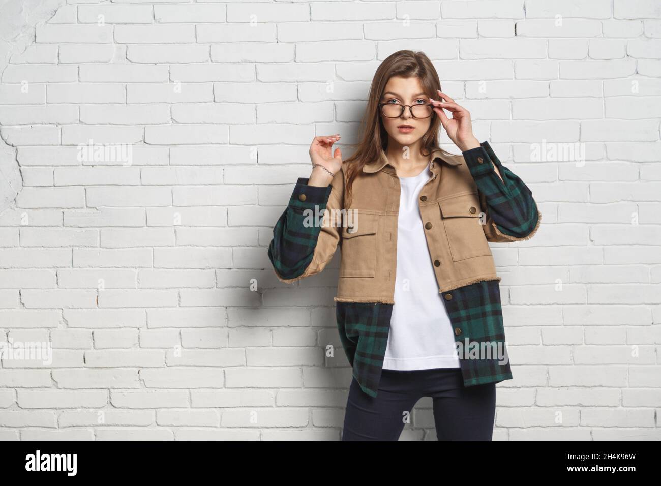 Porträt einer jungen Hipster-Frau in einer Brille über einer weißen Ziegelwand. Sehvermögen konsept. Stockfoto