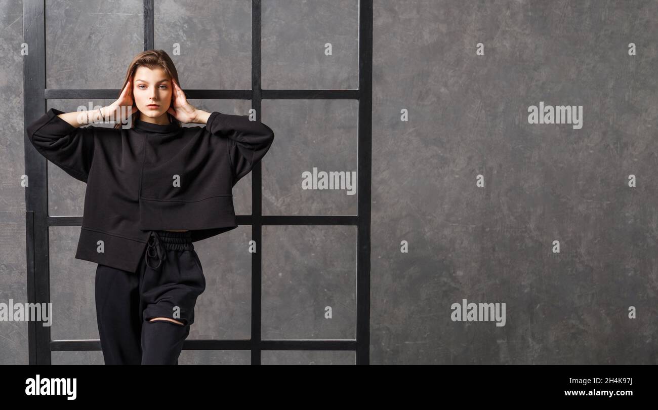 Junge Frau in schwarzer Sportkleidung, Hose und Sweatshirt. Konzept der modischen Sport-Outfit, drinnen Foto. Speicherplatz kopieren. Stockfoto