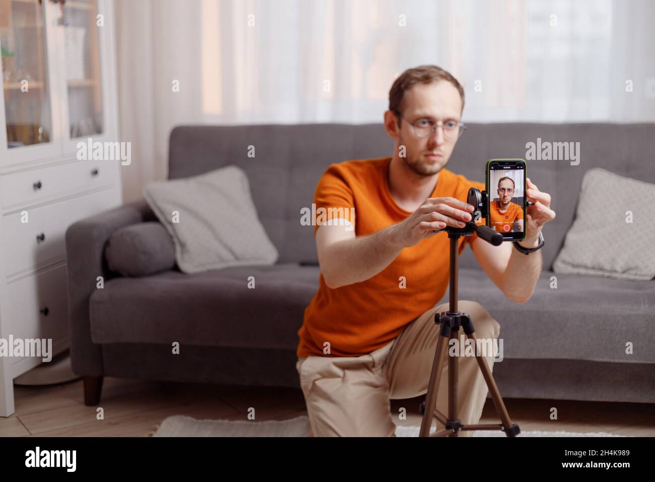 Blogger sein. Kaukasischer intelligenter junger Mann, der zu Hause mit dem Smartphone eine Videokonferenz startet. Stockfoto
