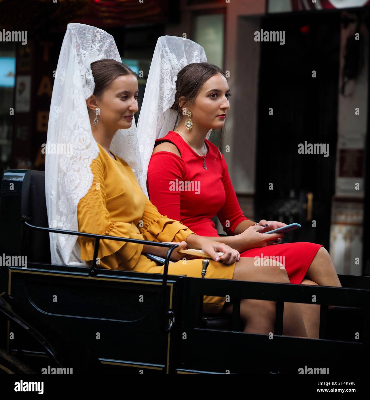 Zwei Frauen in Pferdekutsche tragen die typische spanische Mantilla und kämmen in einer Parade auf dem Fuengirola-Markt. Stockfoto