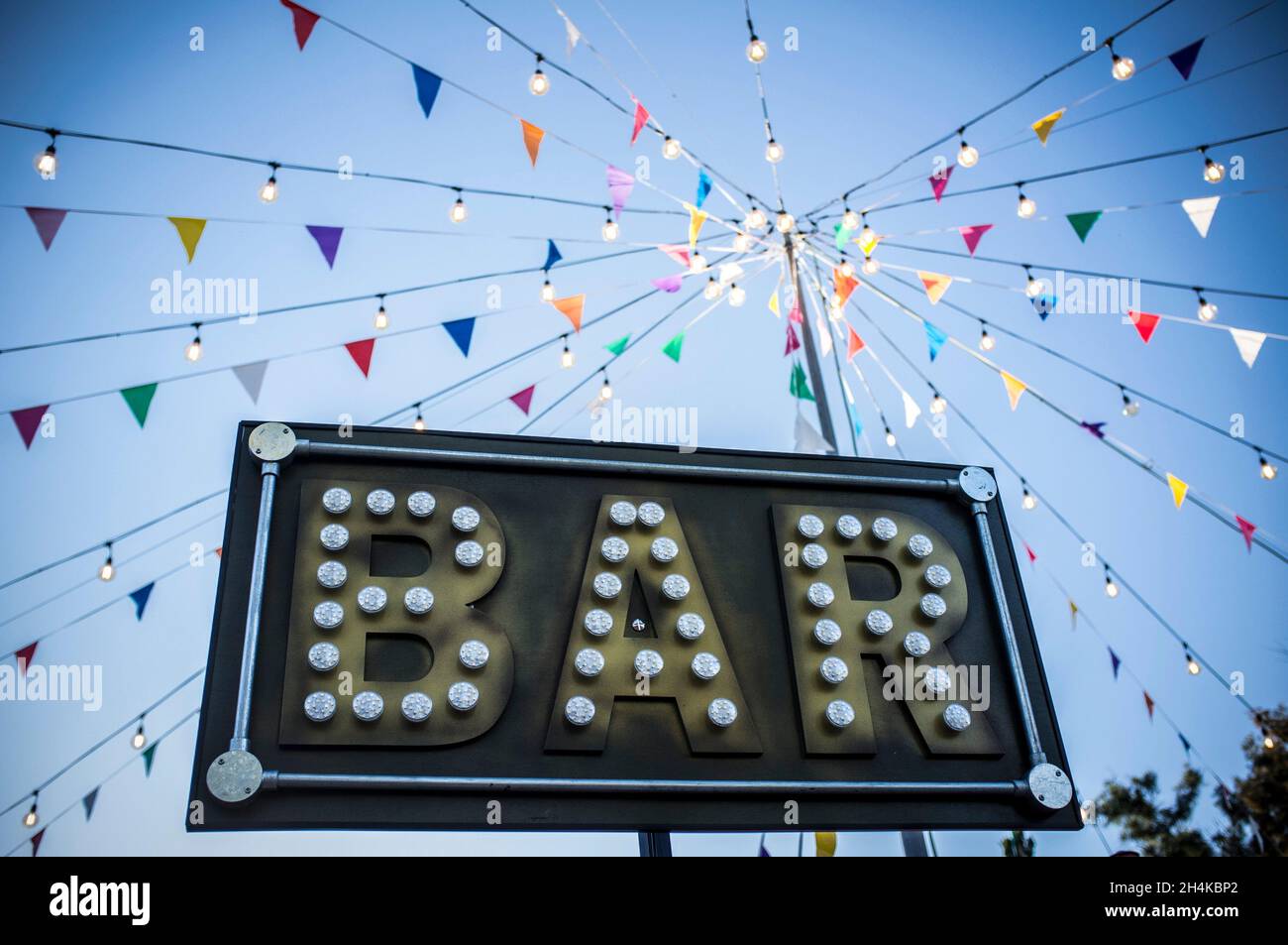 Bar-Banner mit bunten Wimpern und Glühbirnen auf Stange. Im Freien Party Hintergrund. Stockfoto