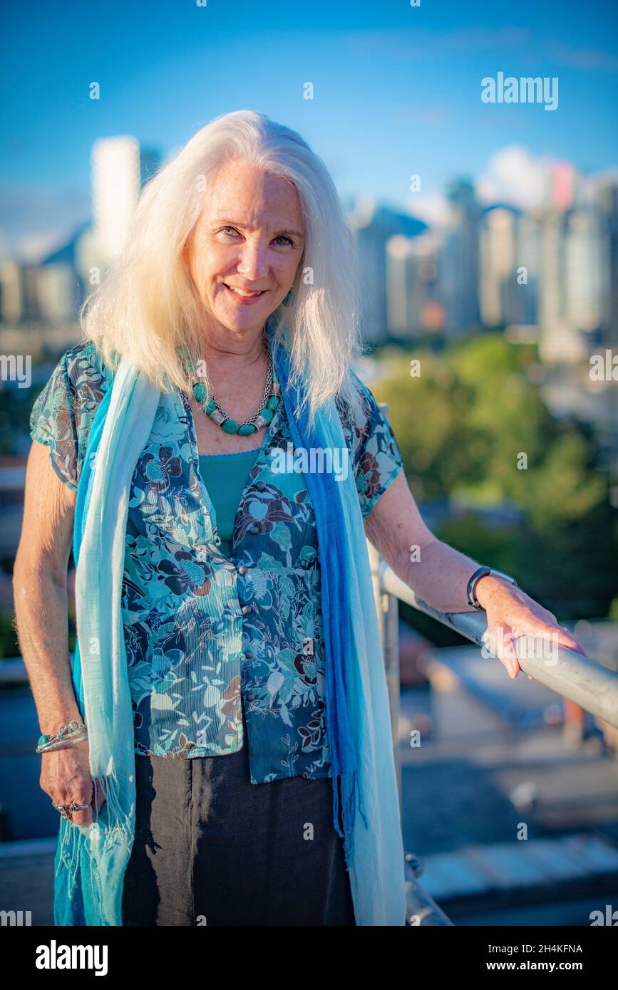 Eine Frau, 70, in einem Porträt auf einem Gerüst mit Blick auf die Innenstadt von Vancouver, BC, Kanada. Stockfoto