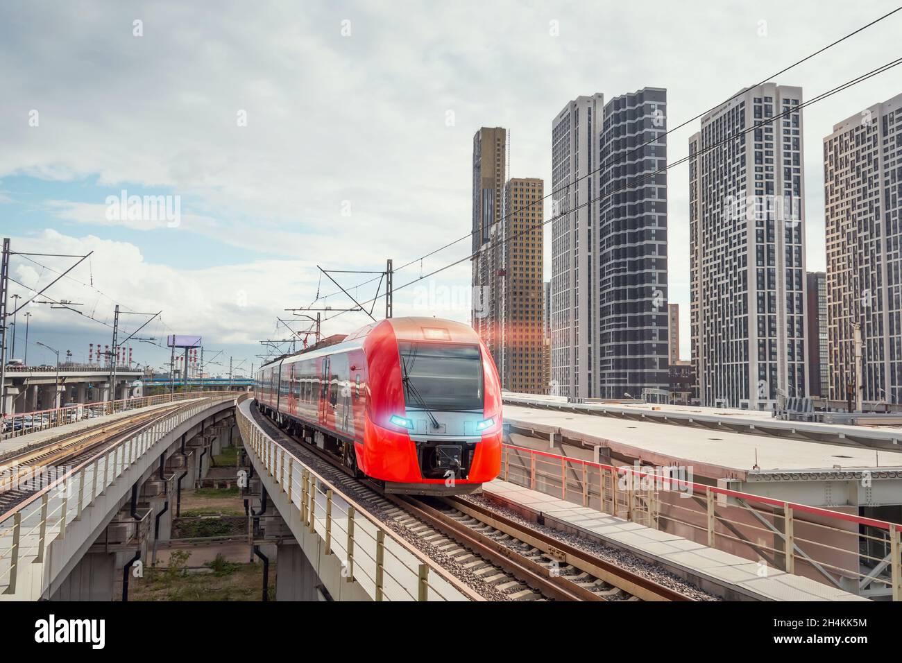 Der elektrische Personenzug fährt mit hoher Geschwindigkeit durch die moderne Stadtlandschaft Stockfoto