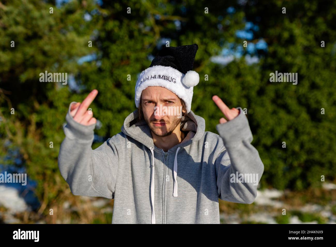 Ein mürrischer junger Mann, der einen schwarzen weihnachtsmann-Hut mit den Worten Bah Humbug trägt Stockfoto