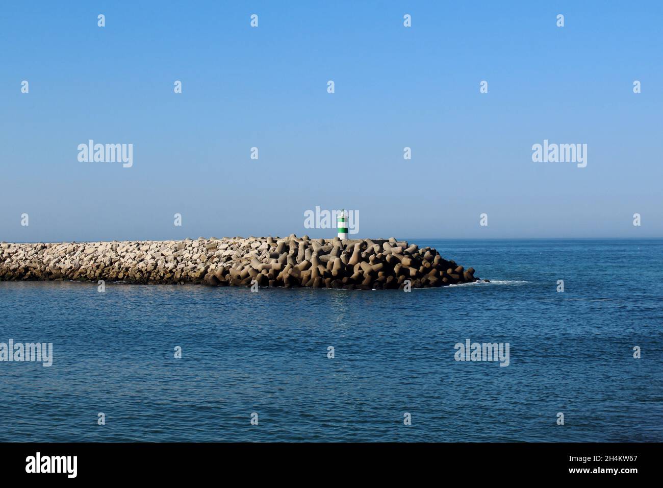 Der grün weiß gestreifen Leuchtturm auf dem Steg am Strand von Nazare. Portugiesische Bezeichnung: Farol Nazaré Pontão. Stockfoto