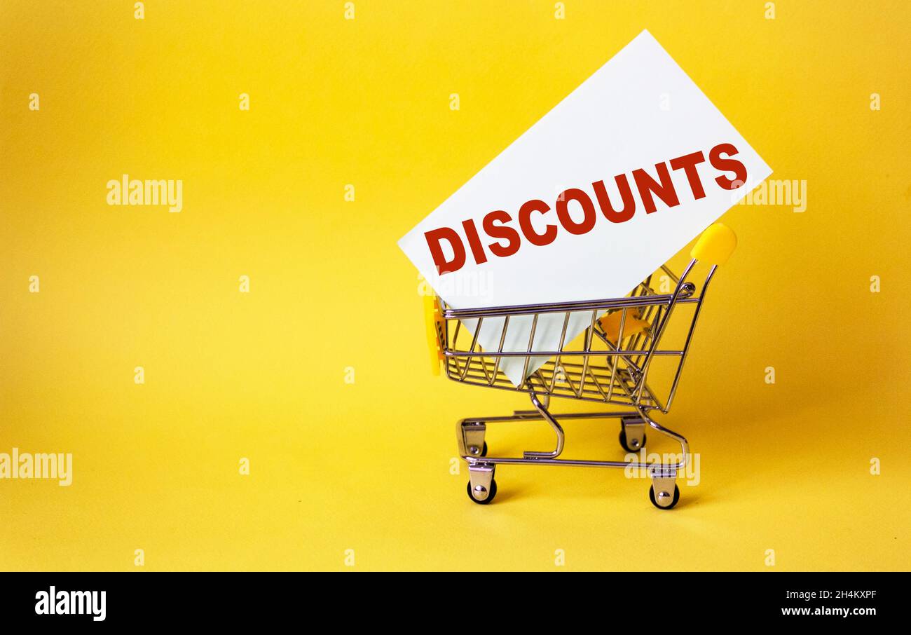 Trolley auf gelbem Hintergrund, in einem Aufkleber mit dem Text RABATTE. Kreative Idee für Online-Shopping, Supermärkte, Rabatte und Black Friday Stockfoto