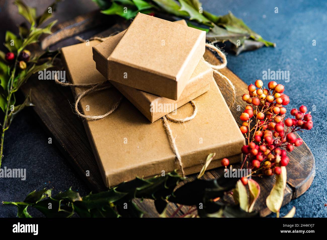 Weihnachtsgeschenkboxen mit roten Beeren, Tannenzapfen und Stechpalme Stockfoto