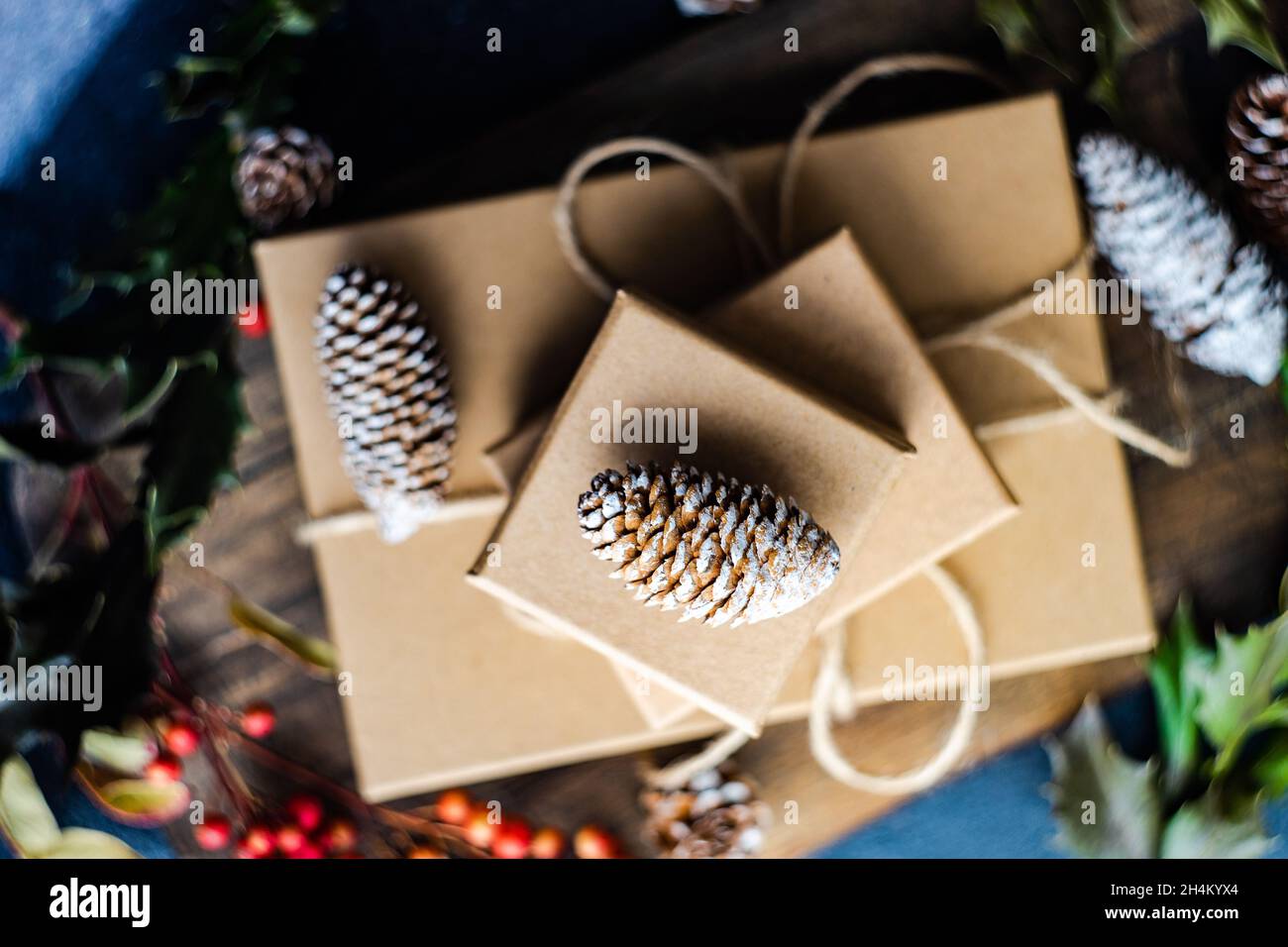 Weihnachtsgeschenkboxen mit roten Beeren, Tannenzapfen und Stechpalme Stockfoto