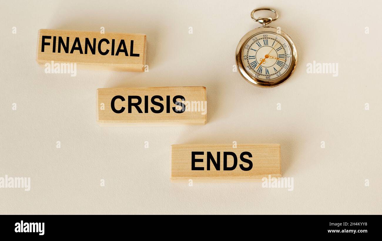 Auf Holzblöcken der Text Ende der Krise und eine Uhr auf weißem Hintergrund Stockfoto