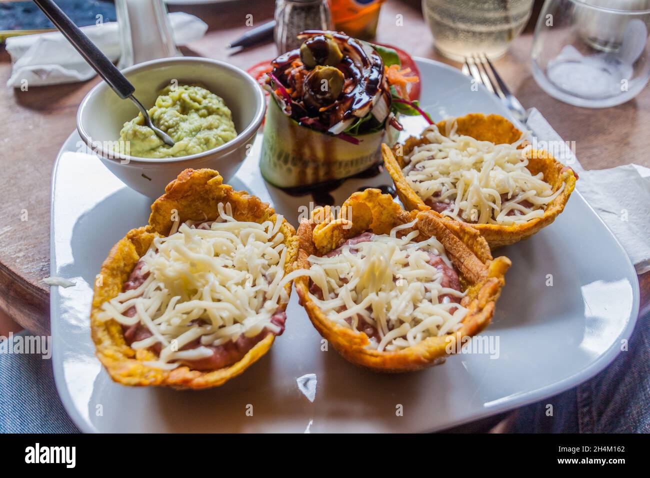 Kolumbianische Mahlzeit. Patacones gebratene Bananen mit Bohnen und Käse. Stockfoto