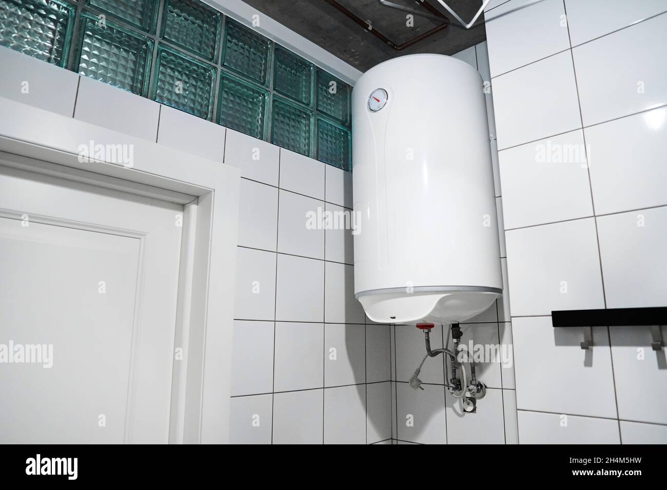 Moderner Gaskessel im Badezimmer. Haushaltsbudget-Warmwasserbereiter, der an der Wand im Kesselraum hängt. Gemeinsamer elektrischer Vorratsbehälter-Warmwasserbereiter Stockfoto