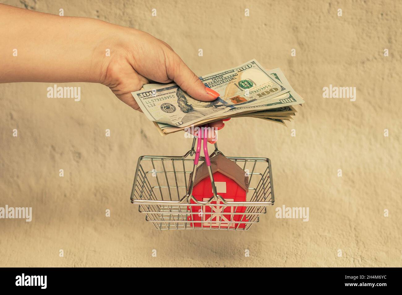 Rotes Haus mit einem Stapel von Dollarscheinen. Das Konzept des Kaufs eines Hauses. Stockfoto