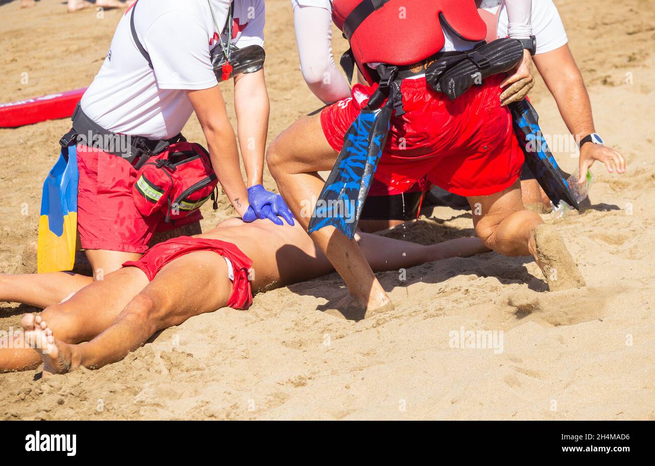 Rettungssimulation und CPR am Strand von Red Cross Rettungsschwimmern in Spanien. Stockfoto