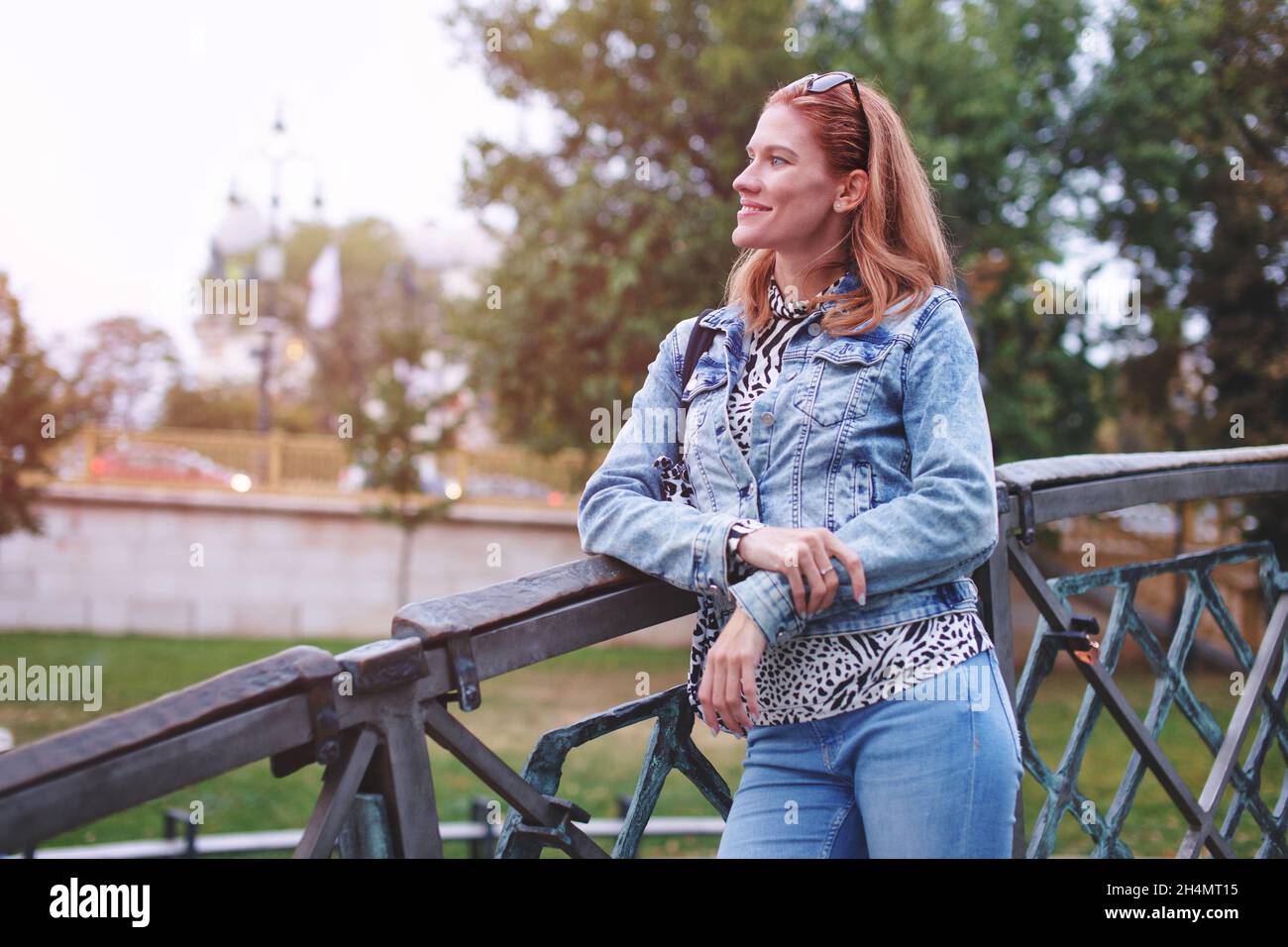 Junge Rotschopf positive kaukasische Frau Blick auf Brücke im Park Stockfoto