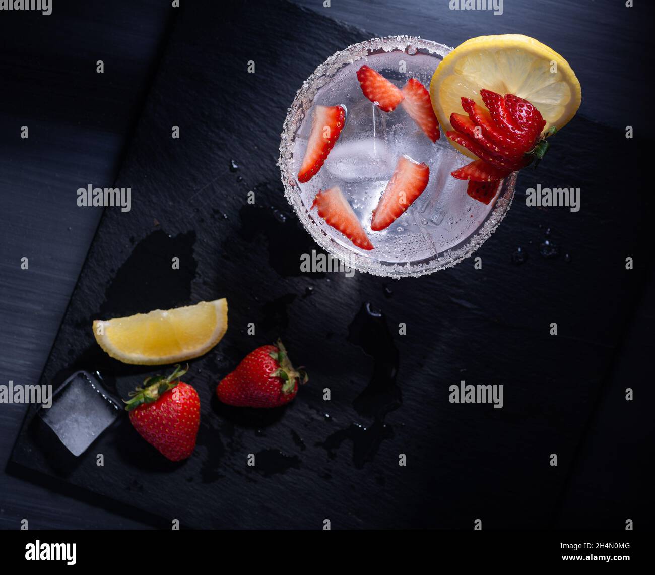 Draufsicht auf ein erfrischendes Getränk mit Erdbeeren und Zitrone auf einer schwarzen Oberfläche Stockfoto