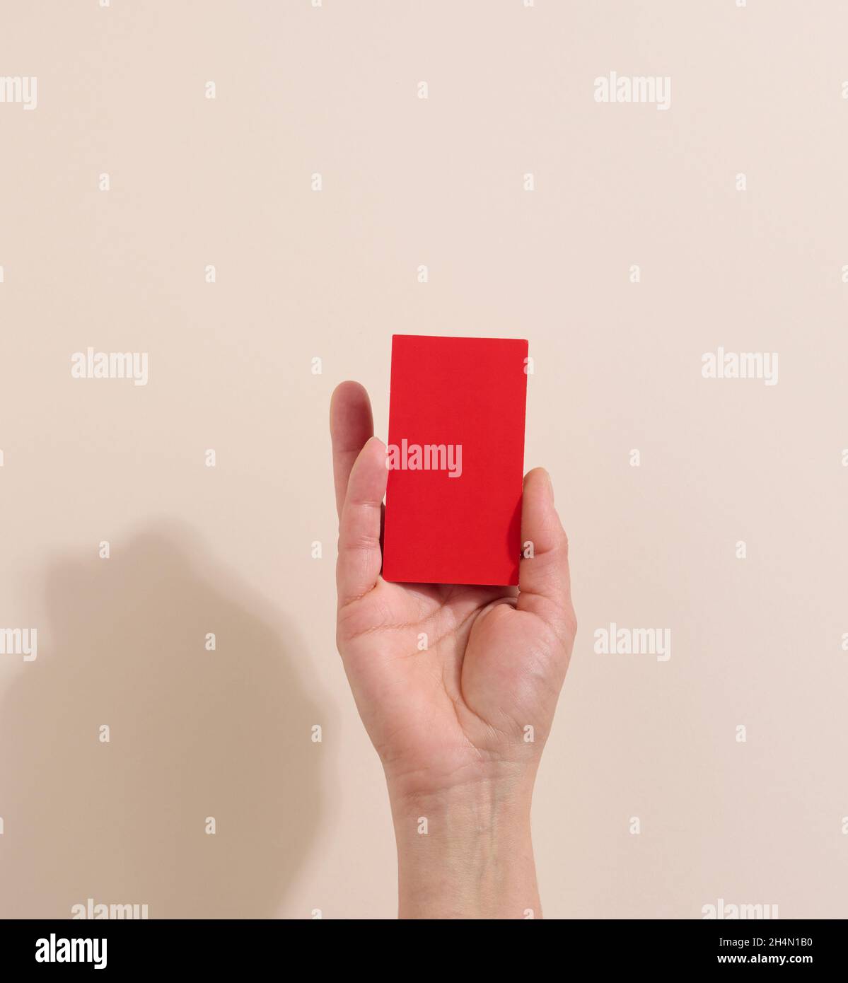 Weibliche Hand hält leeres rotes Papier auf beigem Hintergrund. Kopieren Bild oder Text einfügen, Nahaufnahme Stockfoto