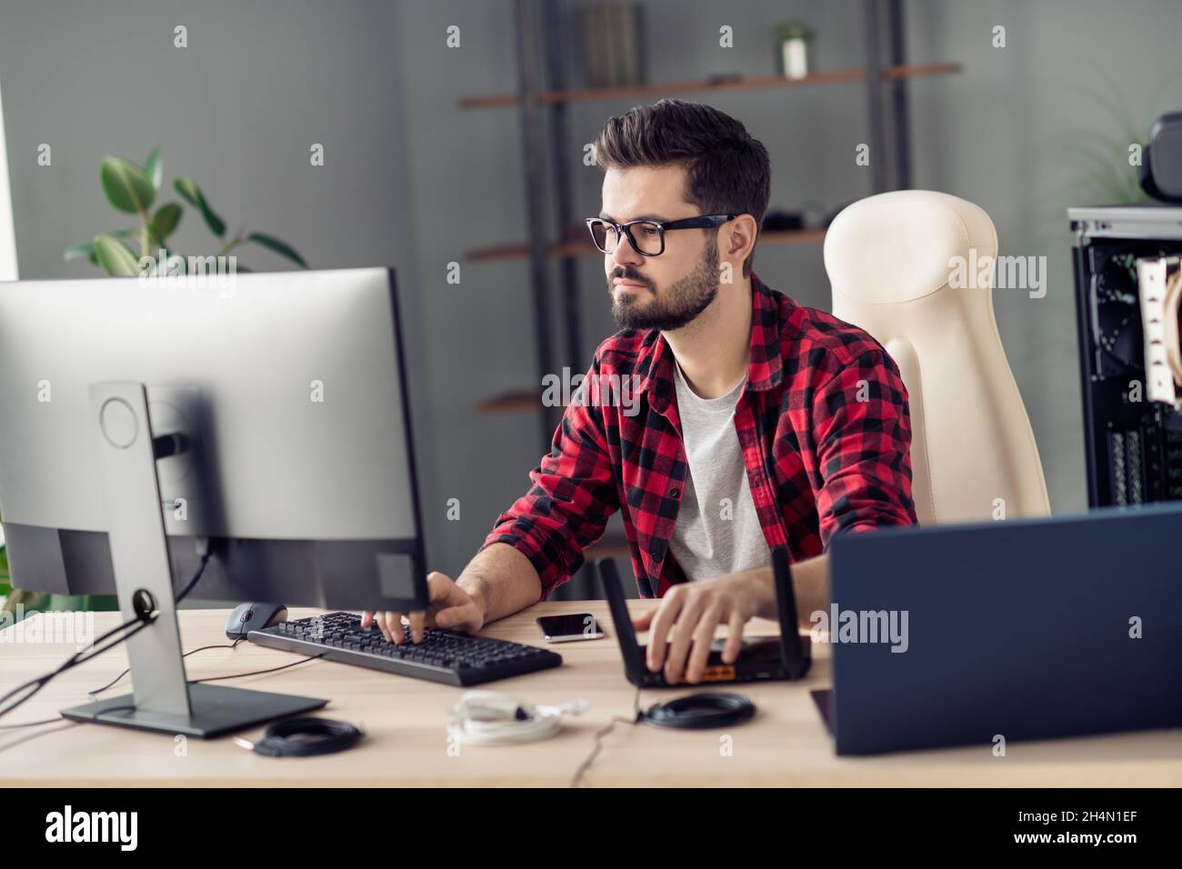 Portrait von attraktiven qualifizierten trendy fokussierten Kerl Einstellung WiFi Router Web wlan Schreibcode im Büro Arbeitsplatz Station innen Stockfoto
