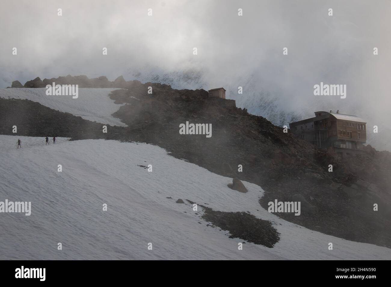 Kleine Wanderer überqueren den Gletscher in der Nähe der Refuge de Tete Rousse in einer Wolke, September, Französische Alpen. Stockfoto