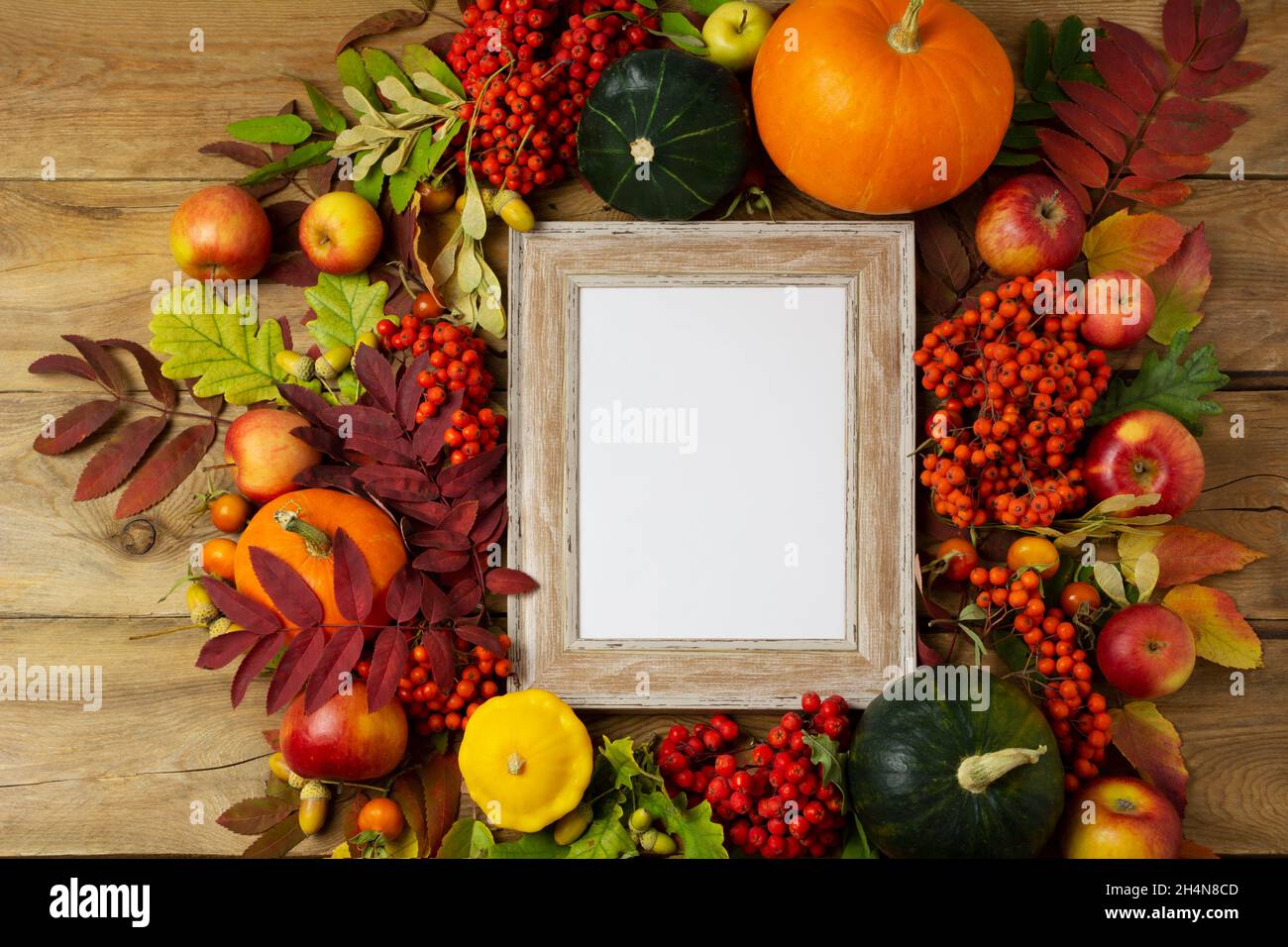 Kleines Holzmodell mit Äpfeln, Kürbissen und Herbstblättern. Leerer Rahmen für Präsentationsgrafiken. Schablonenrahmen für moderne Kunst Stockfoto