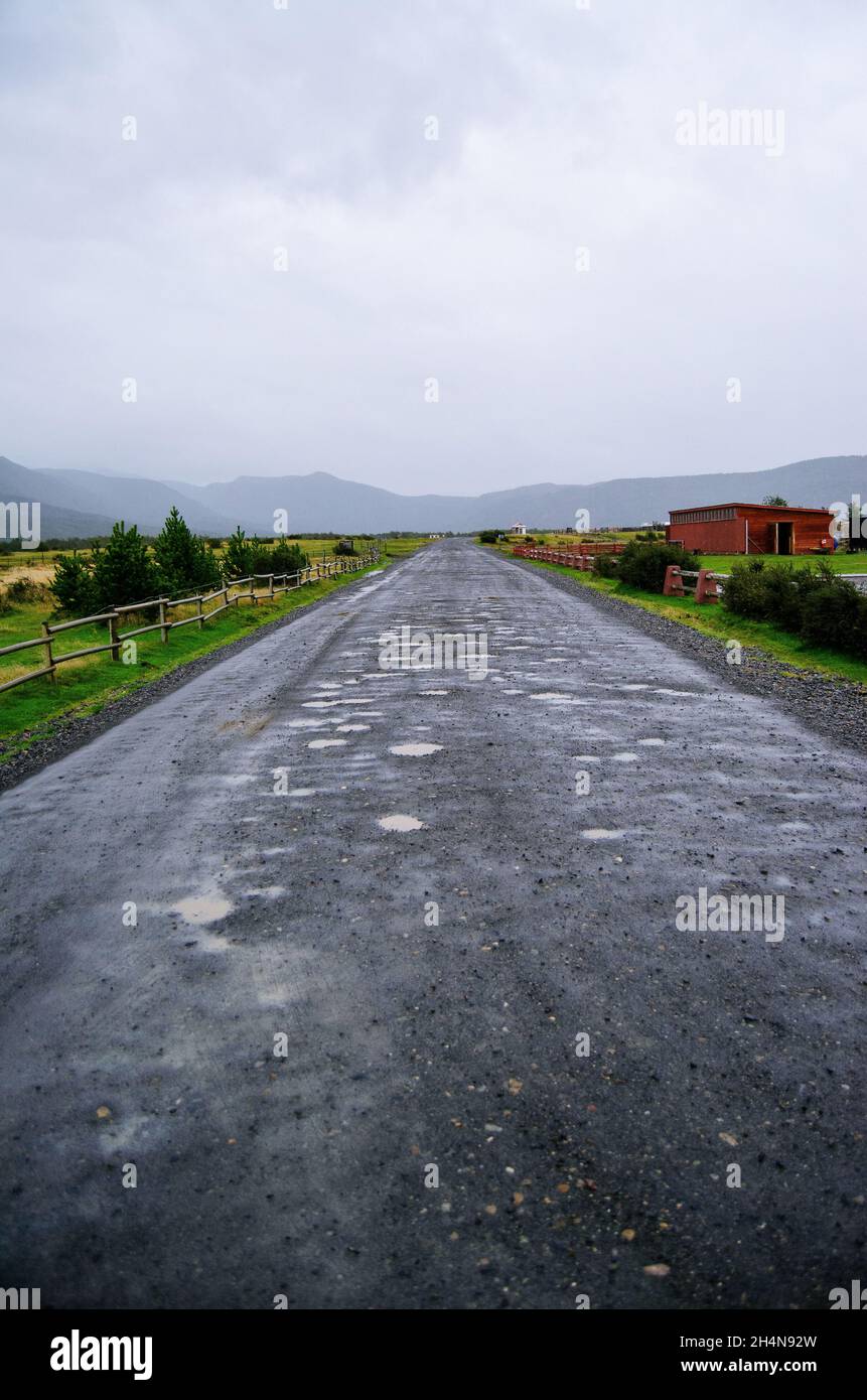 Schotterpiste Straße zu den Bergen in der Ferne mit einem bewölkten Himmel zu lassen Stockfoto