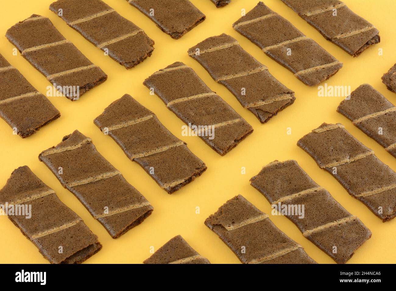 Snacks mit Waffelrolle aus Bananen- und Kakaoschokolade auf gelbem Hintergrund Stockfoto