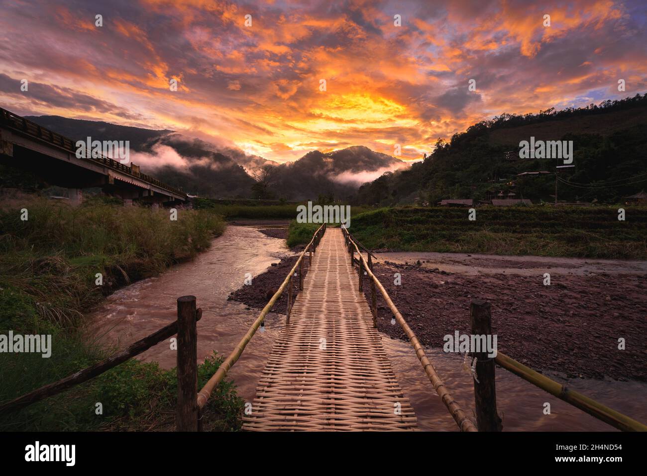 Schöne Landschaft szenische der hölzernen Bambusbrücke mit dem Nebel und dramatischen Himmel Hintergrund in der Sonnenuntergangszeit bei Sapun in der Provinz Nan, nördlich von T Stockfoto