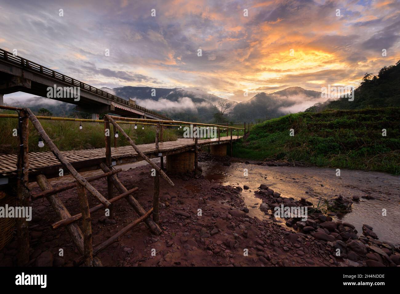 Schöne Landschaft szenische der hölzernen Bambusbrücke mit dem Nebel und dramatischen Himmel Hintergrund in der Sonnenuntergangszeit bei Sapun in der Provinz Nan, nördlich von T Stockfoto