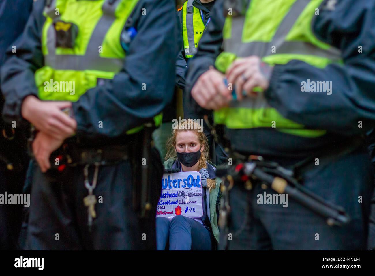 Glasgow, Großbritannien. November 2021. Eine Aktivistin mit einem Plakat klebte sich während des Protestes auf den Bürgersteig vor der SSE (Scottish and Southern Energy plc) in der Waterloo Street.während die UN-Klimakonferenz (26. Konferenz der Parteien (COP26)) weitergeht, Extinction Rebellion und andere Aktivistengruppen zum Klimawandel haben eine Kundgebung in der Glasgow Royal Concert Hall Steps, Buchanan Street, abgehalten und marschieren durch die Straßen des Stadtzentrums von Glasgow. (Foto von Iain McGuinness/SOPA Images/Sipa USA) Quelle: SIPA USA/Alamy Live News Stockfoto