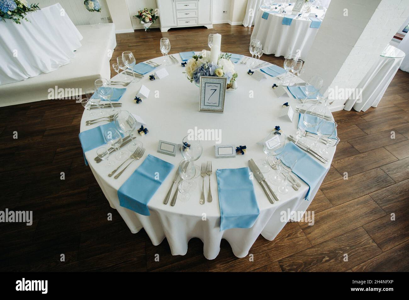 Der Festtisch ist in hellen Farben mit blauen Servietten und Blumen ohne Futter dekoriert. Stockfoto