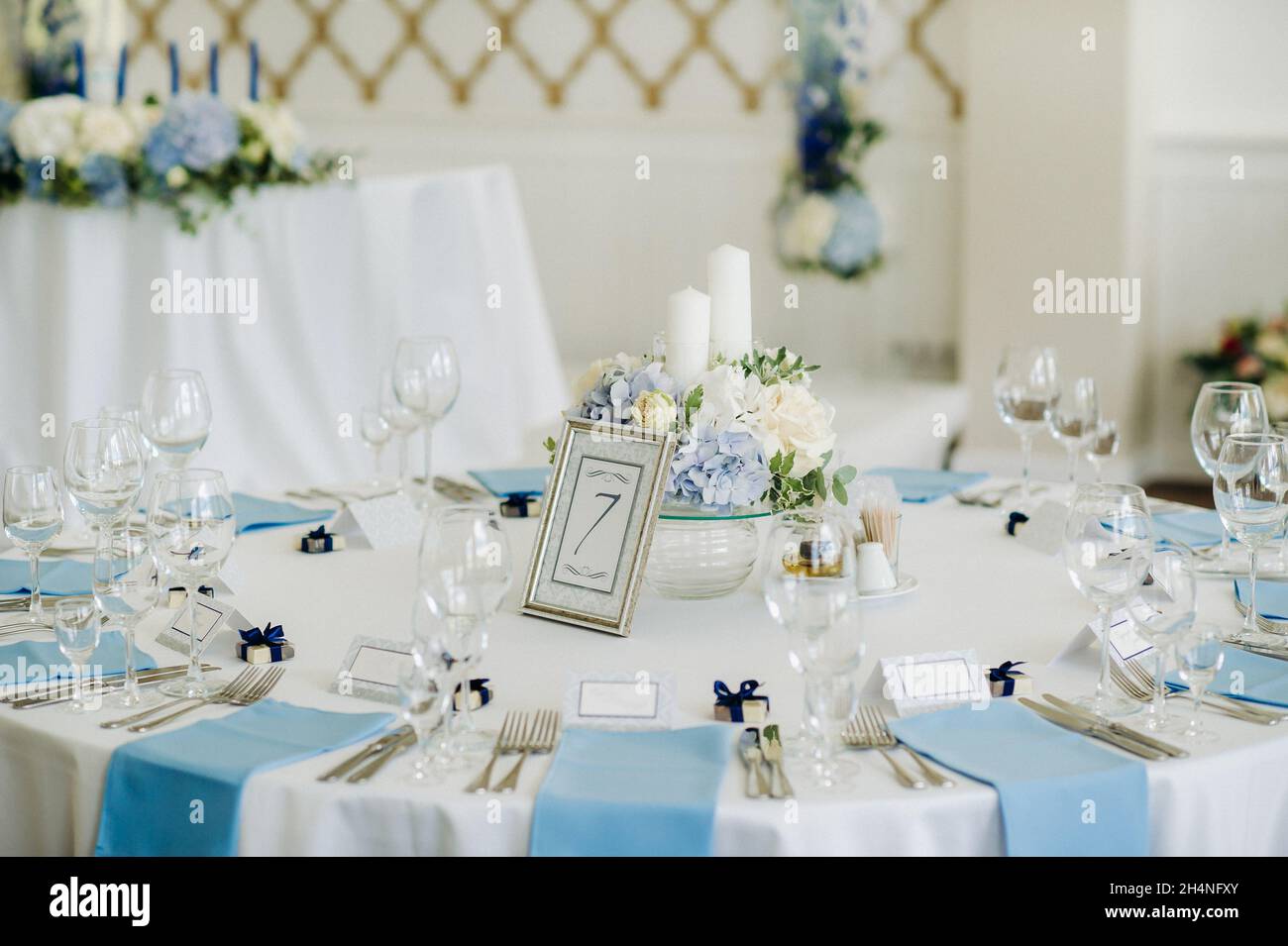 Der Festtisch ist in hellen Farben mit blauen Servietten und Blumen ohne Futter dekoriert. Stockfoto