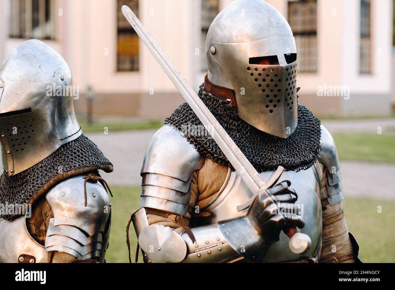 Zwei Ritter in Rüstung auf dem Hintergrund einer mittelalterlichen Burg.Ein mittelalterliches Konzept.Metallische Textur. Stockfoto