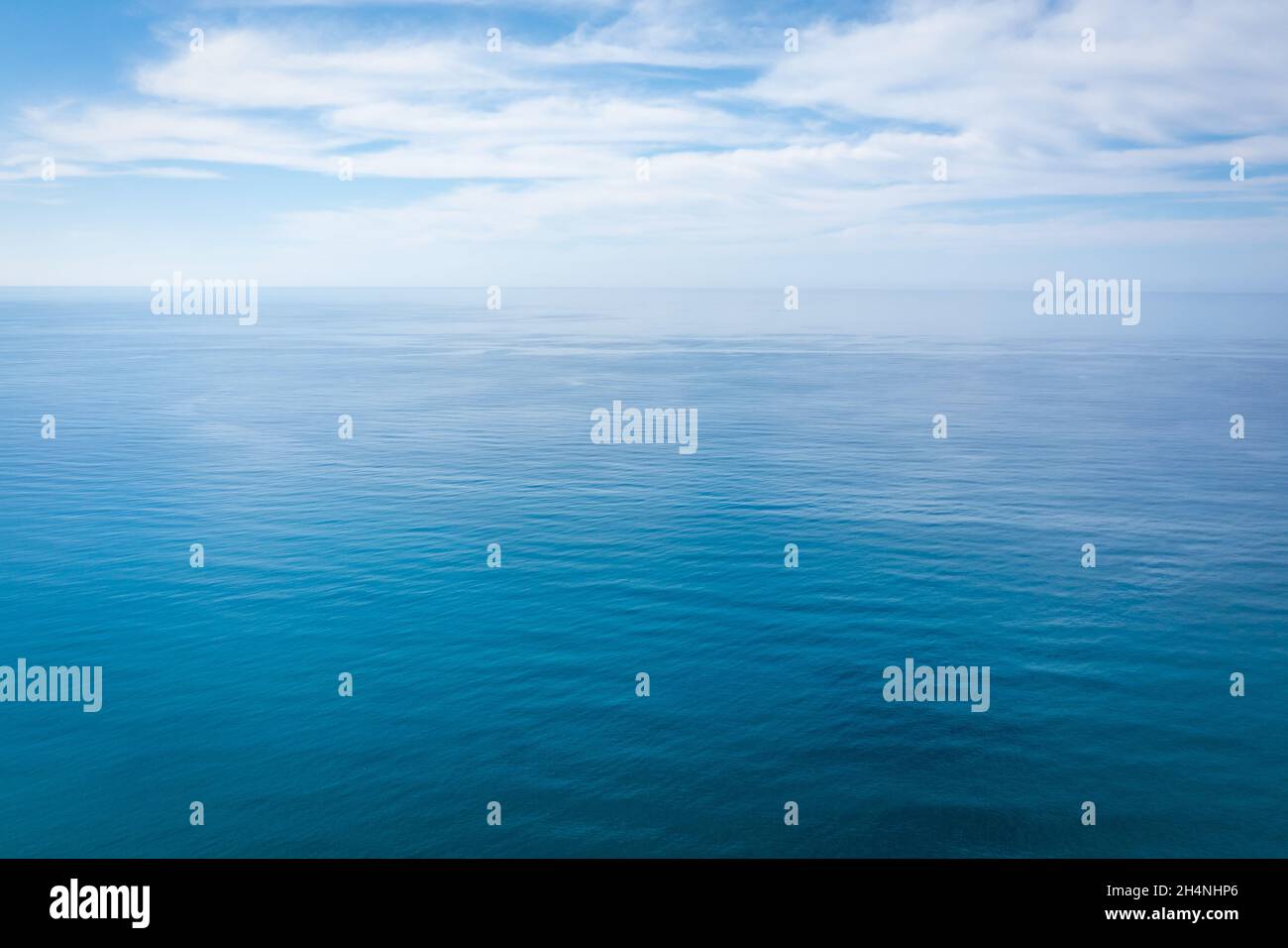 Nahaufnahme des ruhigen, blauen Meerwassers mit Tageslicht und Wolken. Abstrakte Hintergrundtextur. Hochwertige Fotos Stockfoto