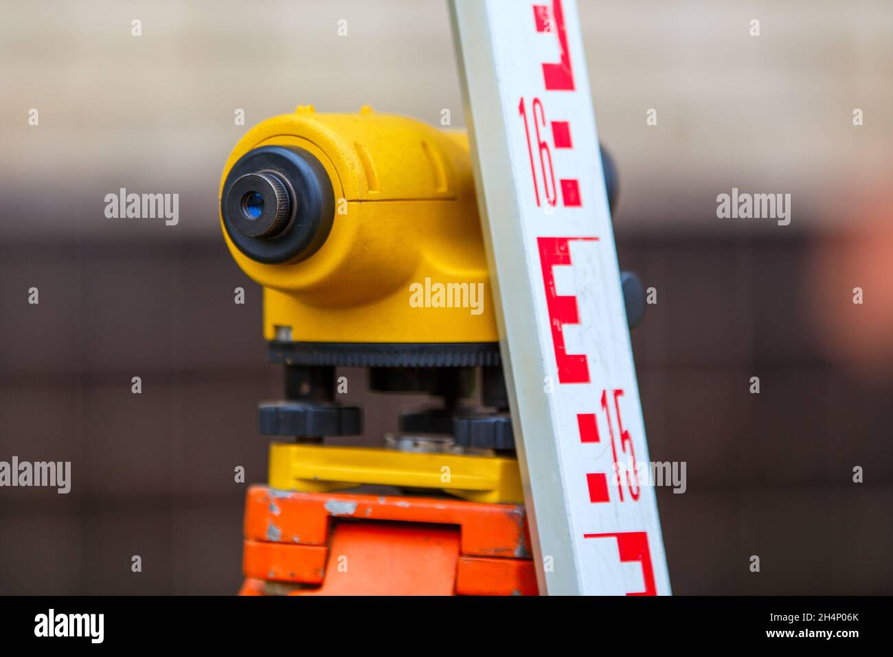 Nahaufnahme eines billigen geodätischen Niveaumessers mit Turmlineal im Freien Stockfoto