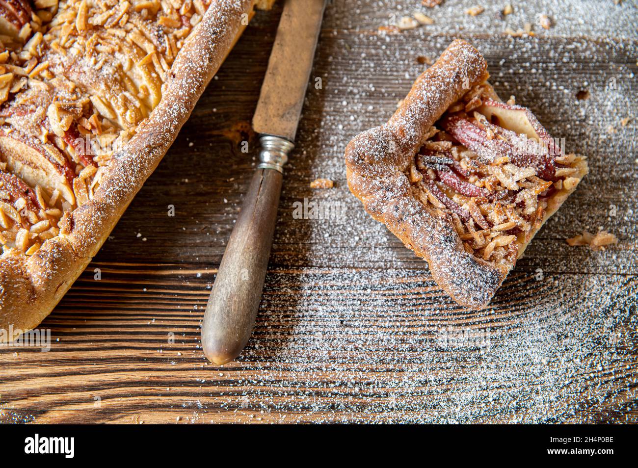 Gesundes Frühstück Apfelkuchen mit Mandel Belag. Gebacken mit Vollkornmehl und Hefeteig. Serviert auf Holzboden Stockfoto