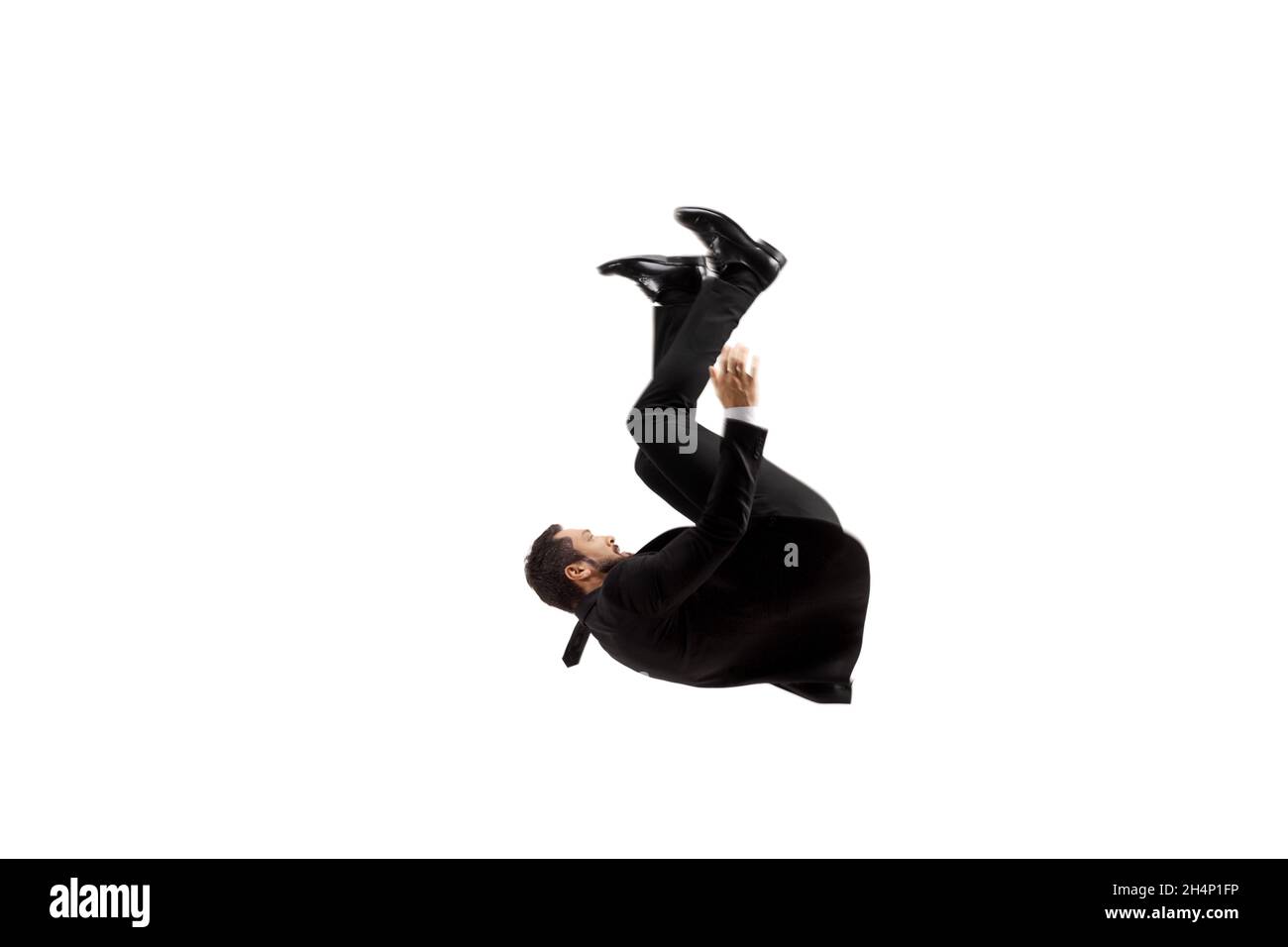 Mann in einem schwarzen Anzug, der auf den Boden fällt, isoliert auf weißem Hintergrund Stockfoto