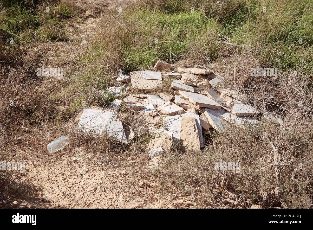 Unwillige weggeworfene Baumaterialien und eine Plastikflasche, die illegal abgeworfen wurden, verschmutzen ein Naturschutzgebiet in der Wüste des Negev-Hochlandes in Israel Stockfoto