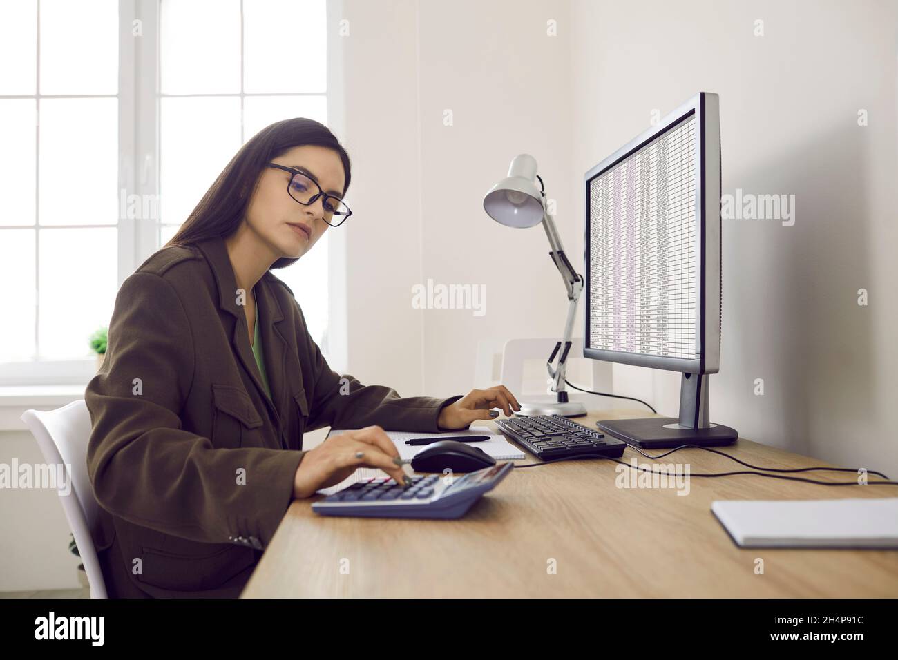 Seriöse Wirtschaftsprüfer in Brillen arbeiten im Büro und mit Computer und Rechner Stockfoto