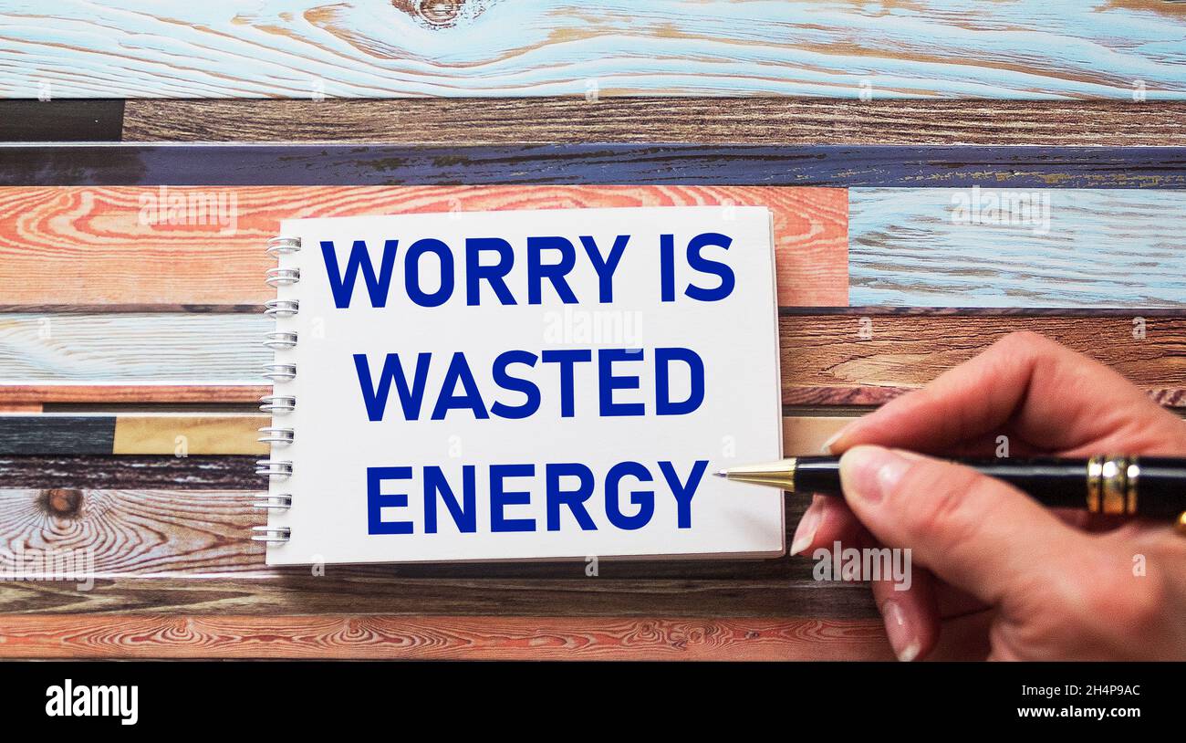 Sorge ist verschwendete Energie – ein inspirierendes Zitat in einem Notizbuch, das in der Hand einer Frau geschrieben ist, eine positive Einstellung und ein Konzept des Optimismus Stockfoto