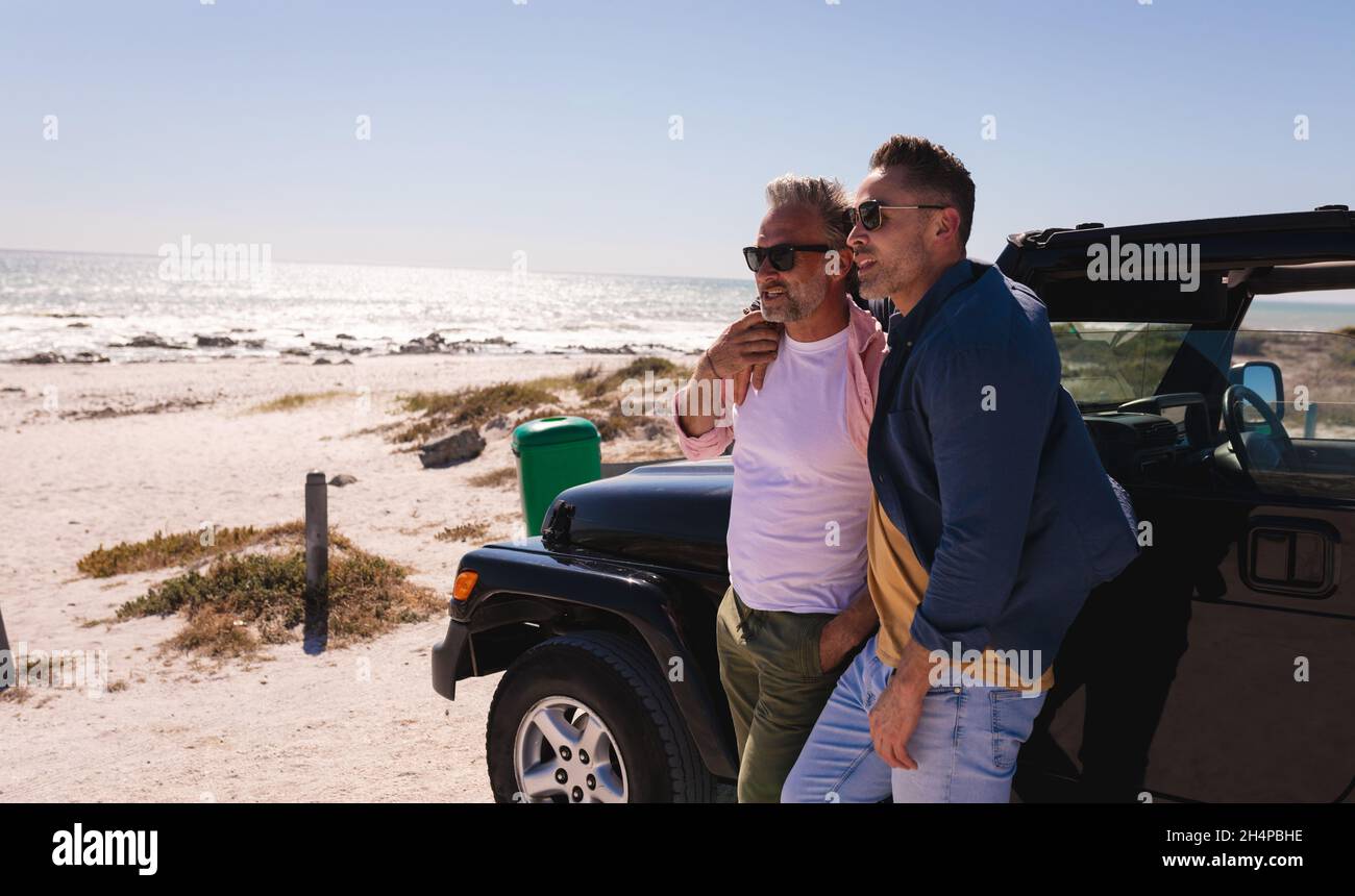 Glücklich kaukasischen Homosexuell männlichen Paar umarmen und genießen die Aussicht mit dem Auto am Meer Stockfoto