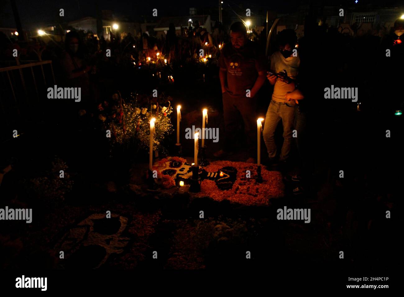 Nicht exklusiv: MEXIKO-STADT, MEXIKO - 2. NOVEMBER 2021: Familienmitglieder schmücken und zünden die Gräber ihrer Lieben an, die im Mixq San Andrés ruhen Stockfoto