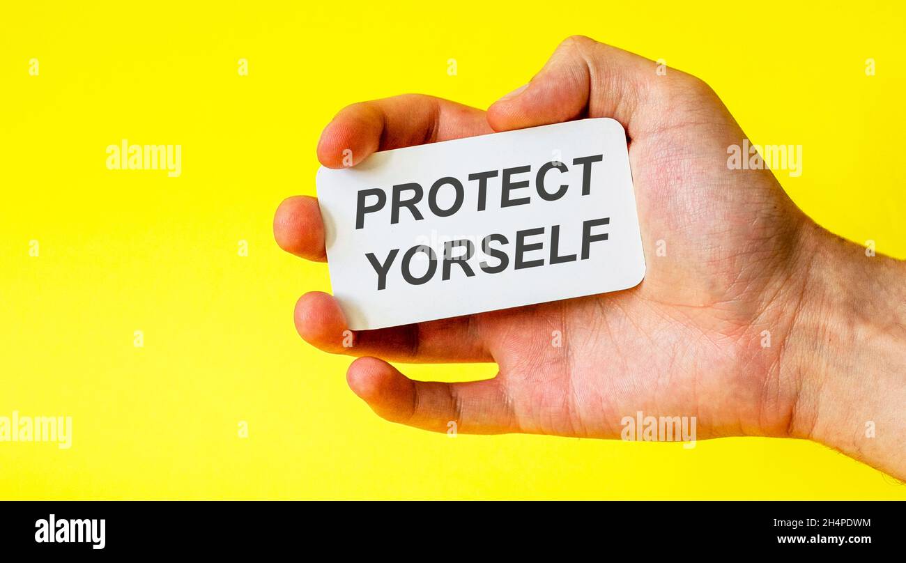 Geschäftsmann hält eine Karte mit dem Text schützen Sie sich auf einem gelben Hintergrund Stockfoto