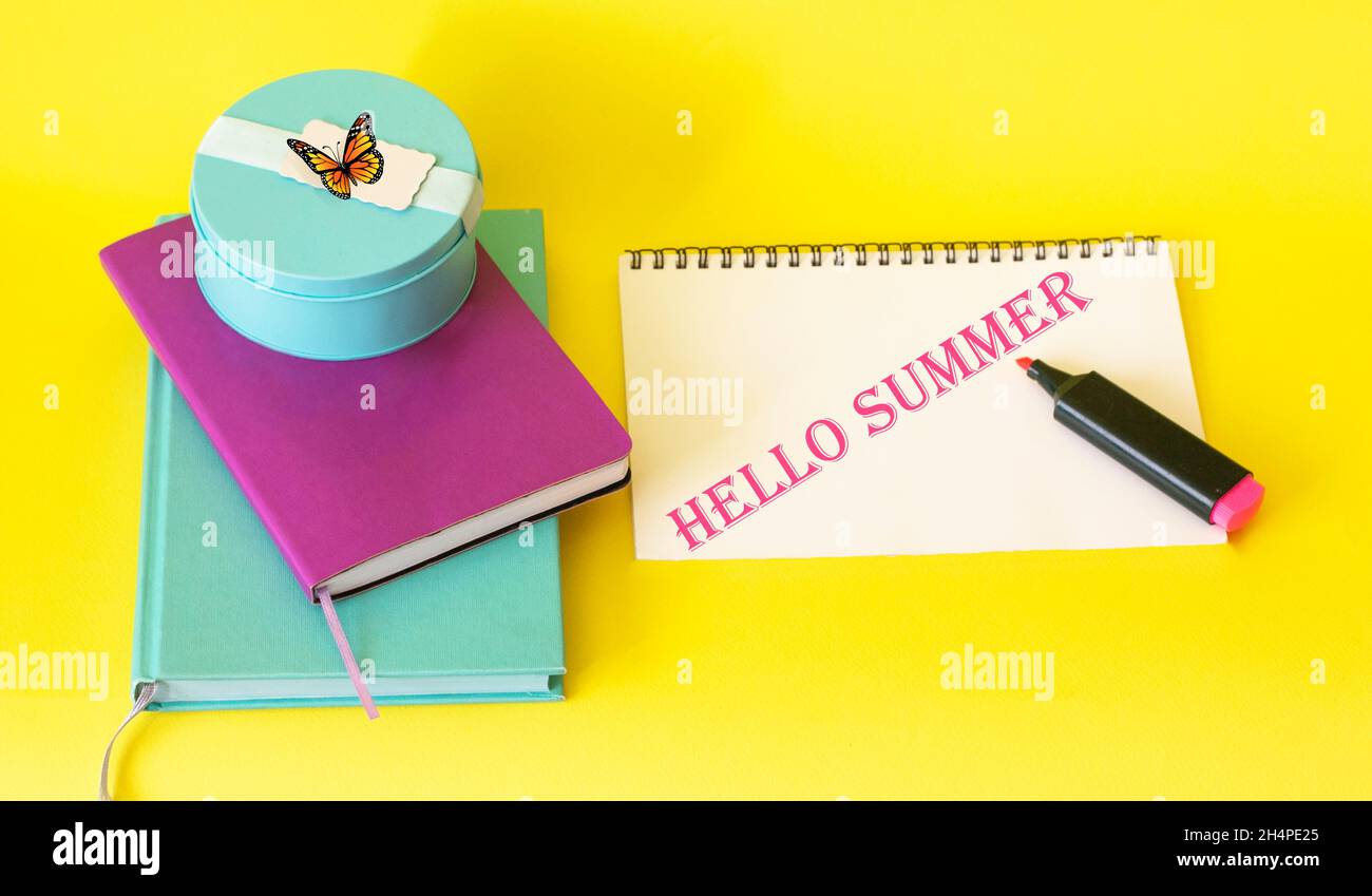 Auf gelbem Hintergrund bunte Notizbücher, Filzstift und Notizbuch mit Text hallo Summer Stockfoto