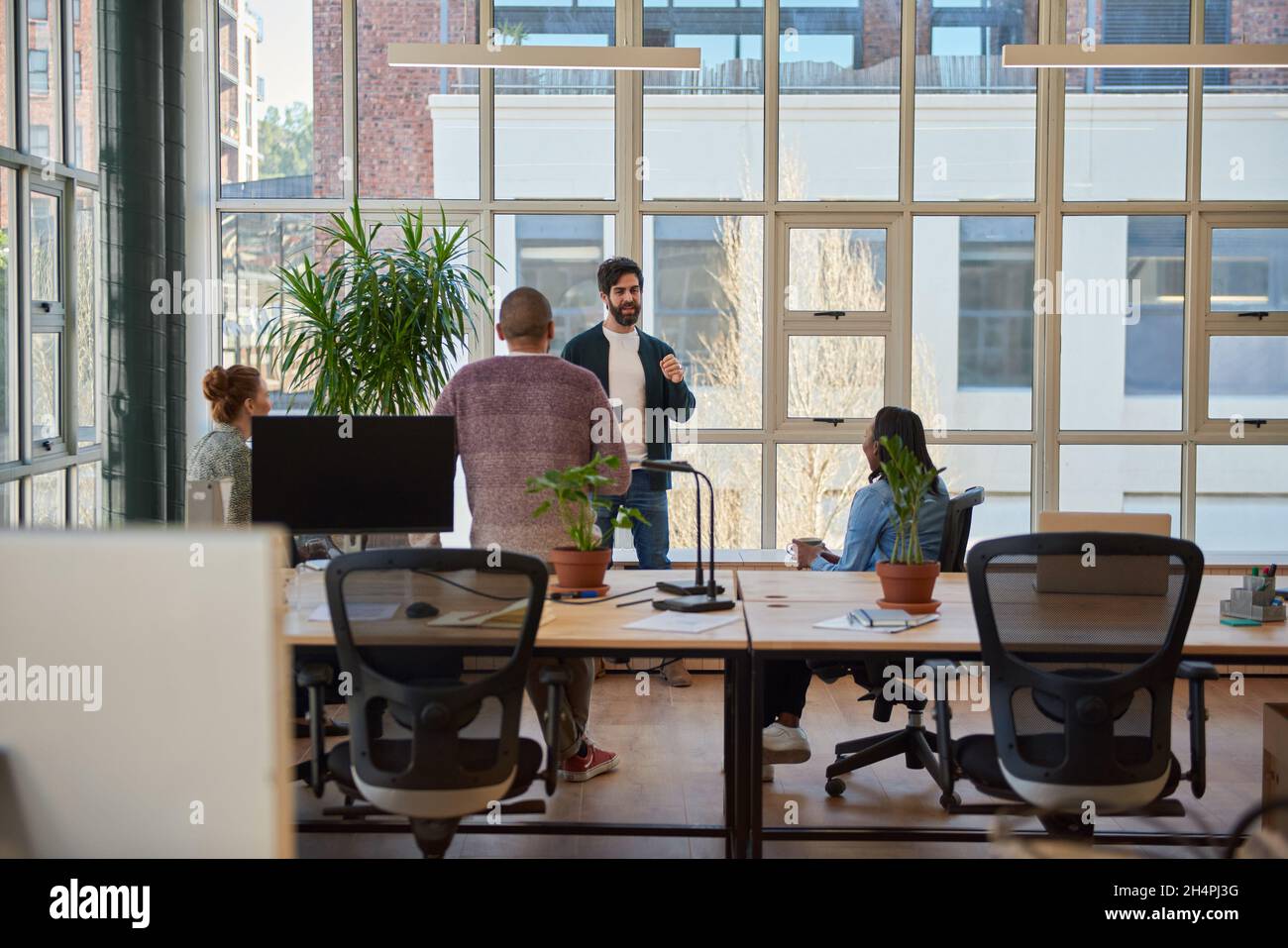 Ein junger Geschäftsmann, der mit Kollegen bei einem Kaffee im Büro spricht Stockfoto