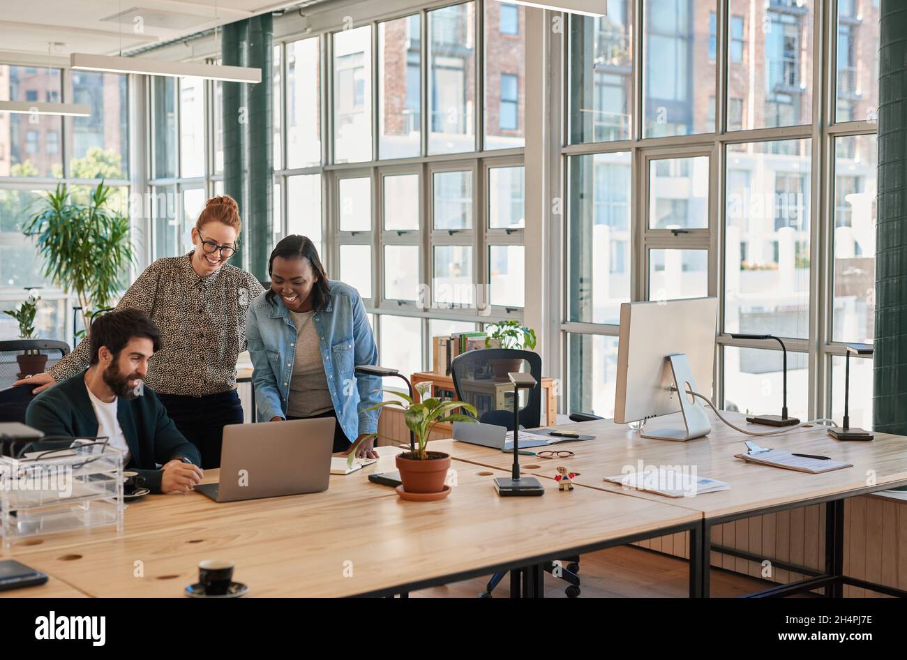 Lachende Gruppe verschiedener Geschäftsleute, die an einem Laptop arbeiten Stockfoto