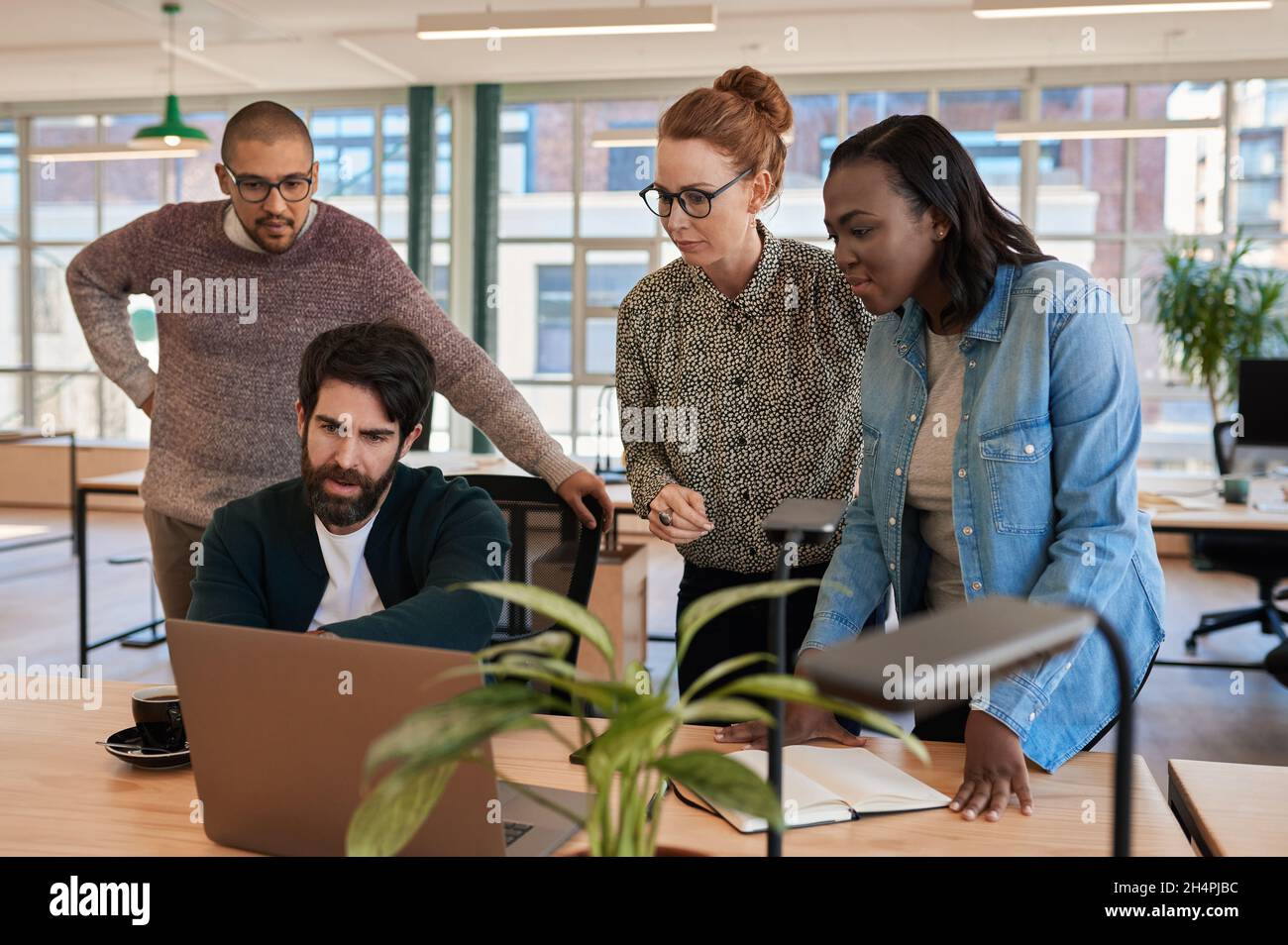 Konzentrierte Gruppe von verschiedenen Geschäftsleuten, die zusammen an einem Laptop arbeiten Stockfoto