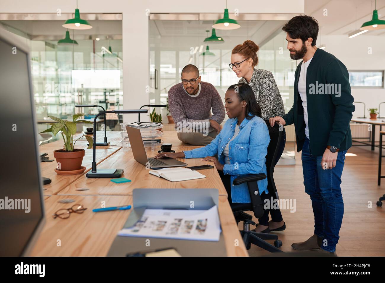 Lächelnde Gruppe verschiedener Geschäftsleute, die zusammen an einem Laptop arbeiten Stockfoto