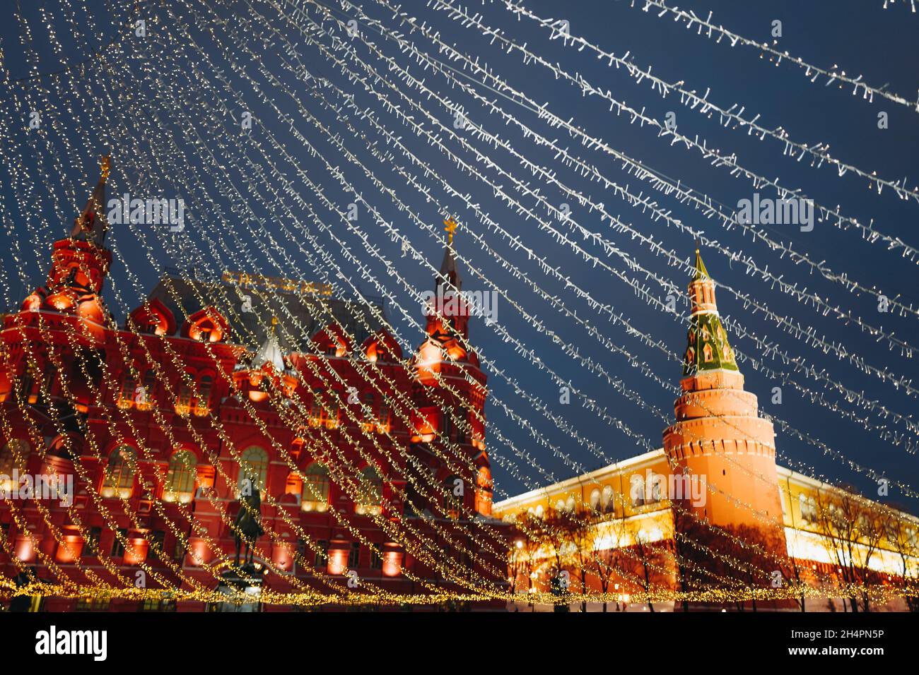 Weihnachtsbaum auf dem Roten Platz Moskau geschmückt mit goldenen Kugeln und Girlanden, funkelnden Lichtern. Girlanden von goldenen Lichtern breiten sich aus der Spitze des t aus Stockfoto