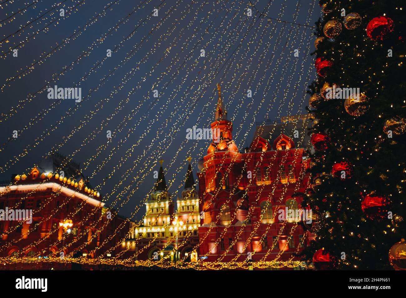 Weihnachtsbaum auf dem Roten Platz Moskau geschmückt mit goldenen Kugeln und Girlanden, funkelnden Lichtern. Girlanden von goldenen Lichtern breiten sich aus der Spitze des t aus Stockfoto